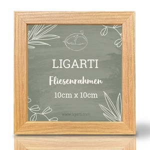 Può includere: Una cornice per foto in legno marrone chiaro con sfondo verde e motivi floreali bianchi. La cornice ha il testo "LIGARTI Fliesenrahmen 10cm x 10cm www.ligarti.com" stampato su di essa.