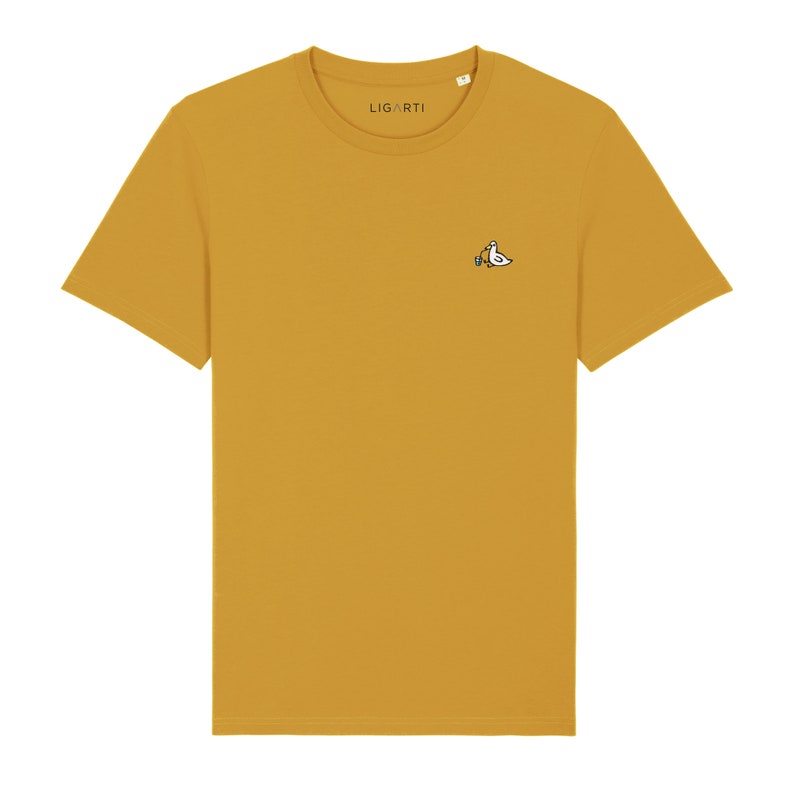May include: A mustard yellow t-shirt with a small embroidered design of a bird holding a paintbrush on the left chest. The t-shirt has a crew neck and short sleeves. The brand name "LIGARTI" is printed on the tag.