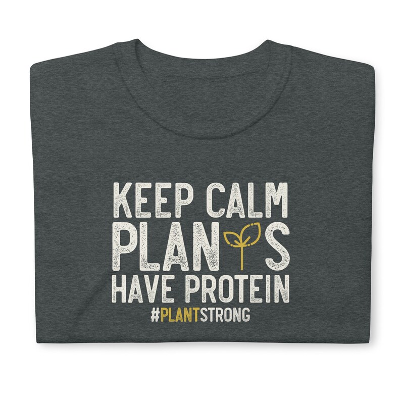 May include: Dark heather grey t-shirt with white text that reads "Keep Calm Plants Have Protein" and a small green plant graphic. The text "#PlantStrong" is below the main text.