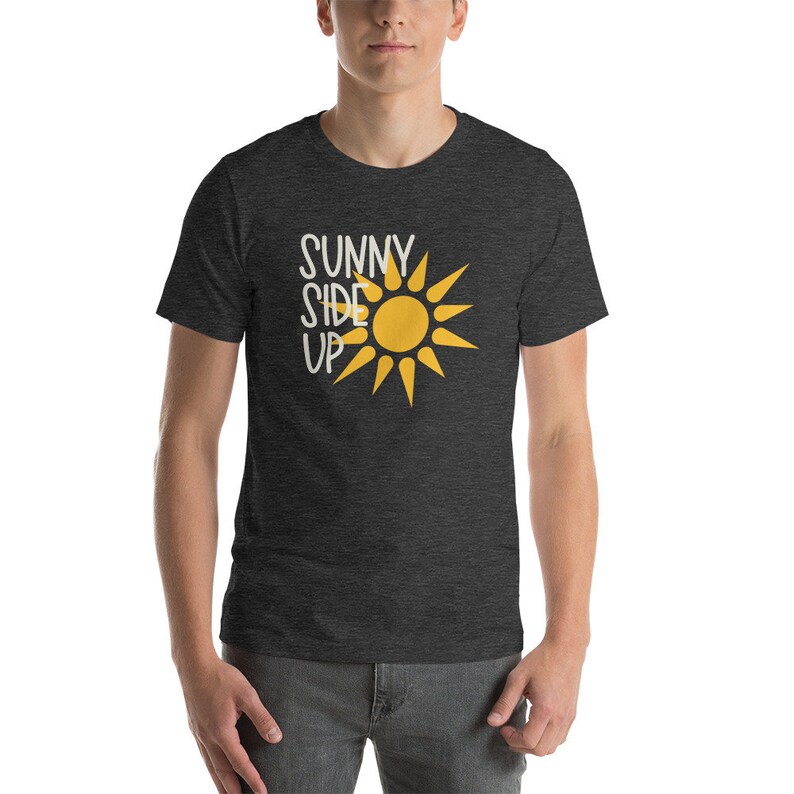 May include: A dark heather grey t-shirt with a yellow sun graphic and the text "Sunny Side Up" in white.