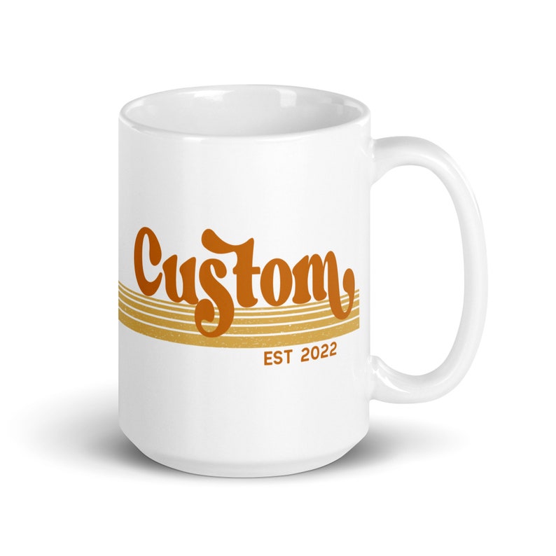May include: White ceramic mug with a brown and gold design. The mug has the word "Custom" in a retro font with gold stripes and the text "EST 2022" below.