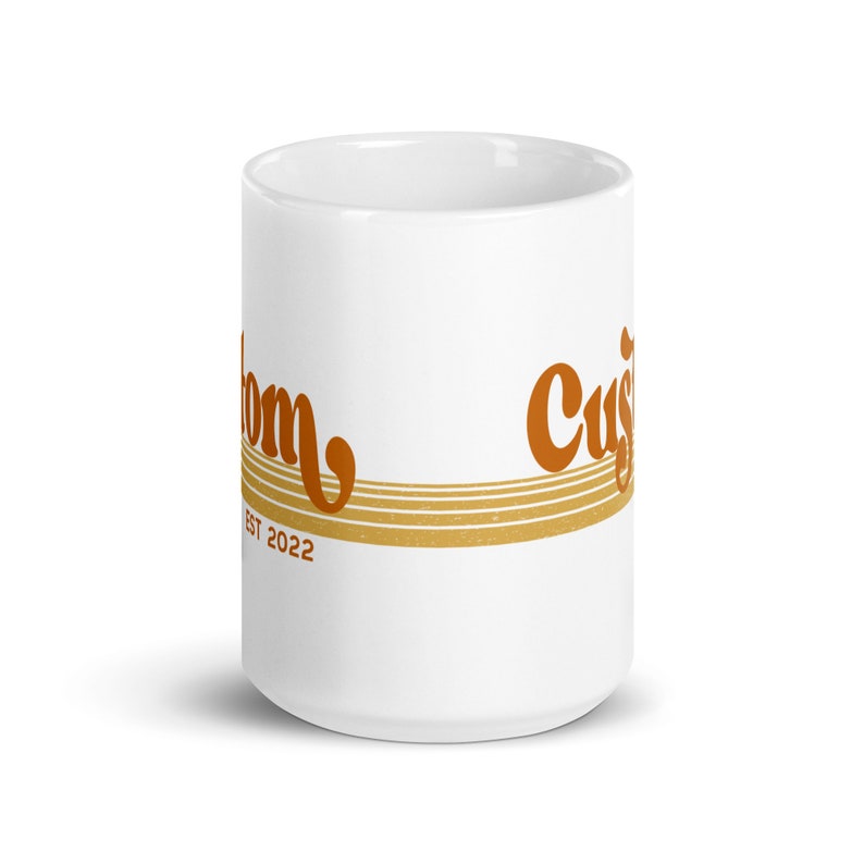 May include: White ceramic mug with a brown and orange design that says "Custom" and "Est 2022".