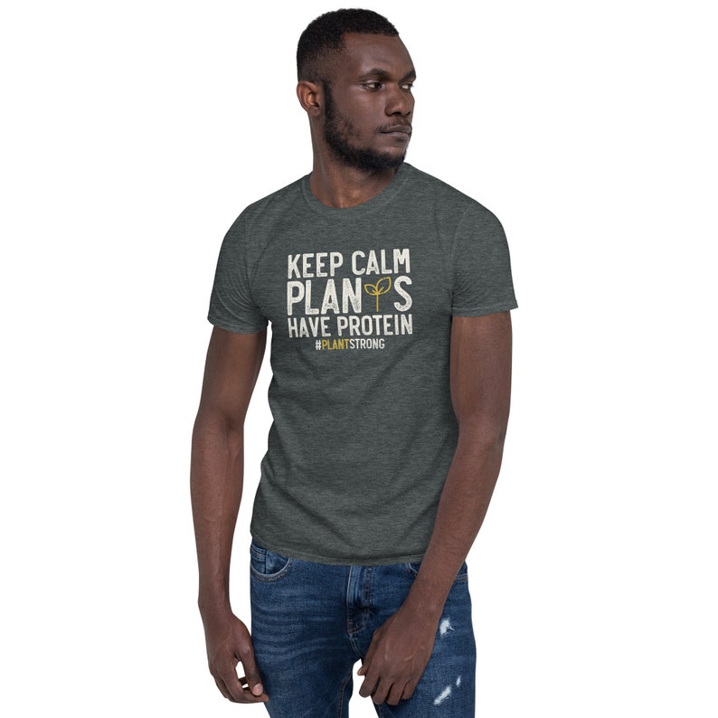 May include: A dark heather grey t-shirt with a white graphic that says "Keep Calm Plant's Have Protein #PlantStrong".