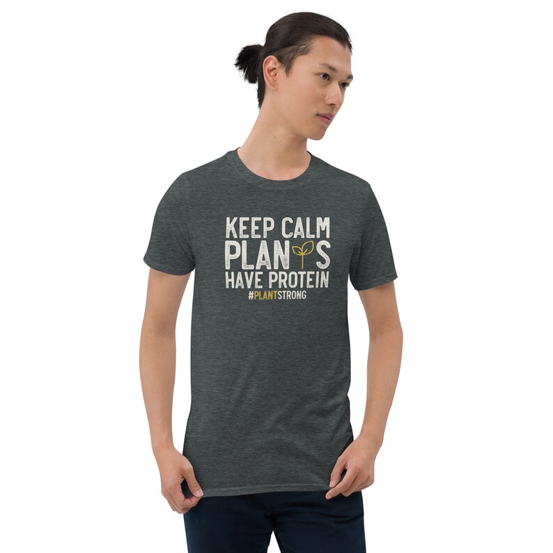 May include: A dark heather grey t-shirt with a white graphic that says "Keep Calm Plant's Have Protein #PlantStrong".