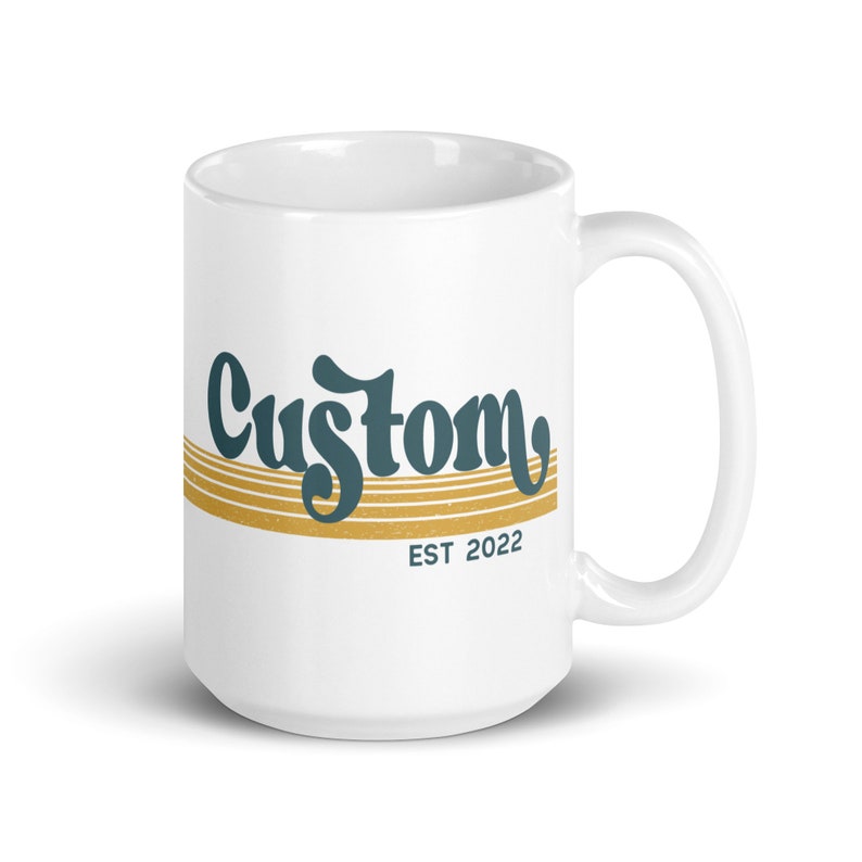 May include: White ceramic mug with a teal blue and gold design. The mug features the word "Custom" in a stylized font with gold stripes and the text "EST 2022" below.
