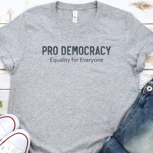 May include: A gray t-shirt with the text "PRO DEMOCRACY" and "Equality for Everyone" printed on the front.