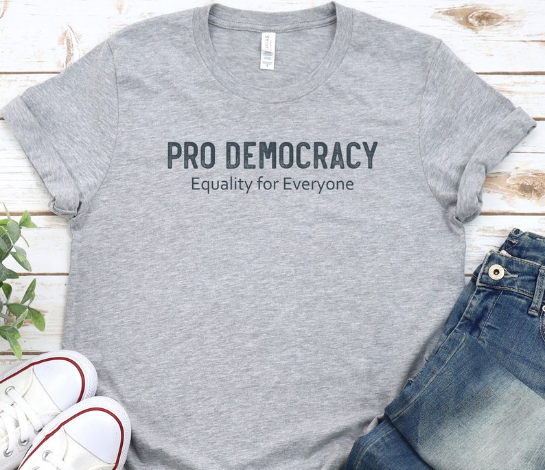 May include: A gray t-shirt with the text "PRO DEMOCRACY" and "Equality for Everyone" printed on the front.