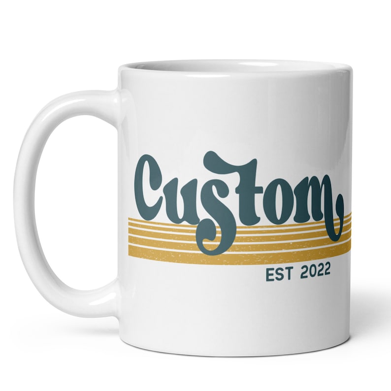 May include: White ceramic mug with a teal blue and gold design. The mug features the word "Custom" in a retro font with gold stripes and the text "EST 2022" below.