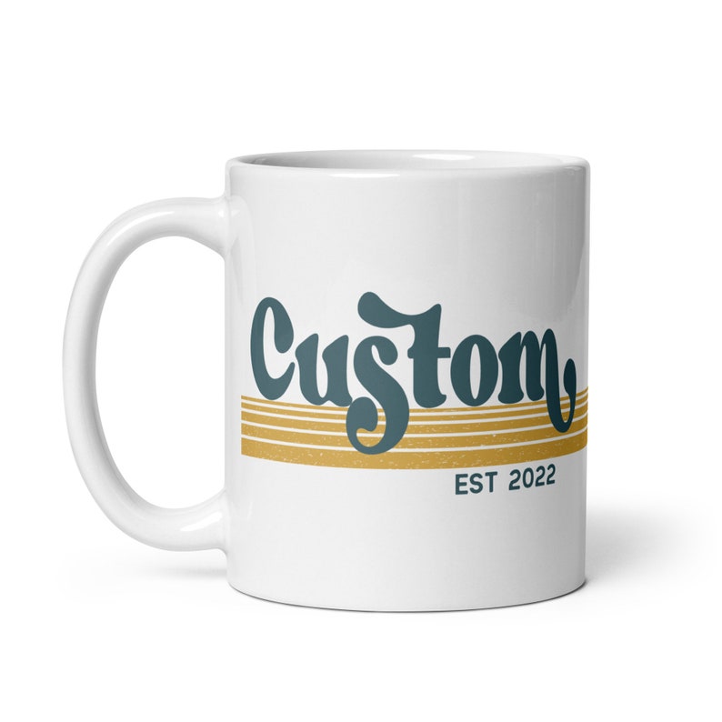 May include: White ceramic mug with a blue and gold design. The design features the word "Custom" in a retro font with gold stripes and the text "EST 2022" below.