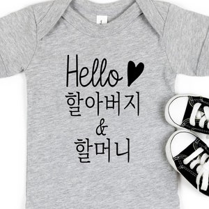 May include: Gray baby onesie with black text that says "Hello 할아버지 & 할머니" with a black heart.
