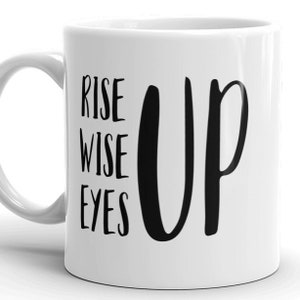 May include: White ceramic coffee mug with black text that reads "Rise Wise Eyes Up".