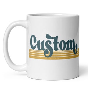May include: White ceramic mug with a teal blue "Custom" graphic with gold stripes.