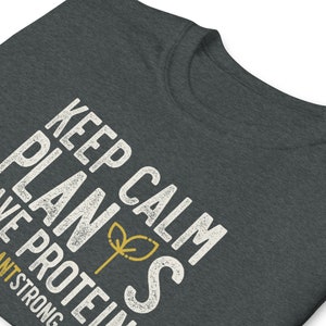 May include: A dark grey t-shirt with the text "Keep Calm Plants Have Protein" in white with a small green plant icon. The text is distressed and has a vintage look.