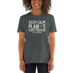 May include: A dark heather grey t-shirt with a white graphic that reads "Keep Calm Plants Have Protein #PlantStrong".