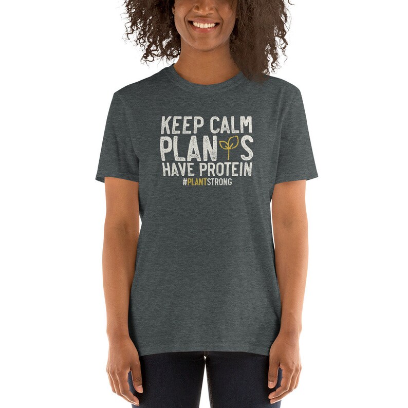 May include: A dark heather grey t-shirt with a white graphic that reads "Keep Calm Plants Have Protein #PlantStrong".