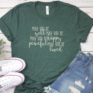 May include: A green t-shirt with the text "MAY YOU BE well MAY YOU BE peaceful MAY YOU BE loved" printed in white on the front.