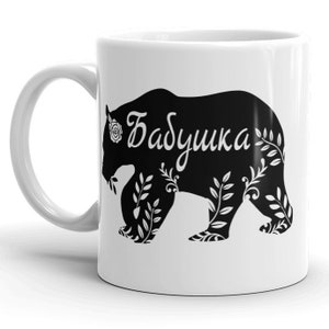 May include: White ceramic mug with a black silhouette of a bear with floral details and the word "Бабушка" in white lettering.