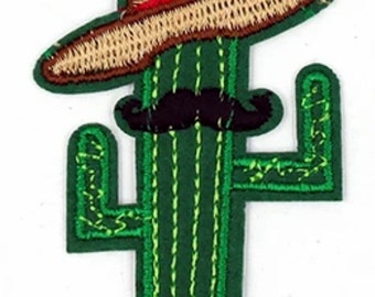 Könnte beinhalten: Grüner Kaktus mit einem braunen Sombrero und einem schwarzen Schnurrbart. Der Kaktus ist mit grünem und gelbem Garn gestickt.
