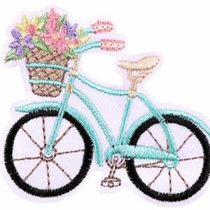 Könnte beinhalten: Ein türkisfarbenes Fahrrad mit einem Korb voller bunter Blumen. Das Fahrrad hat schwarze Räder und einen braunen Sattel.