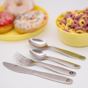 Könnte beinhalten: Ein Set silbernes Kinderbesteck mit einer Gabel, einem Messer und zwei Löffeln. Jedes Stück hat ein kleines Tiermotiv auf dem Griff.