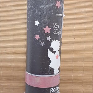 Pu&ograve; includere: Una candela grigia con un nastro rosa e dettagli di perle bianche. La candela ha una silhouette bianca di un angelo con stelle rosa e il testo "Zur Taufe" sul davanti. La candela &egrave; su una base di legno. Il testo "Romy 04.09.20" &egrave; sul fondo della candela.