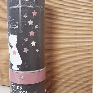 Pu&ograve; includere: Una candela battesimale grigia con un nastro rosa e un bordo di perle bianche. La candela presenta una silhouette bianca di un angelo con stelle rosa e una croce. Il testo "Zur Taufe" e "Romy 04.09.2021" &egrave; scritto sulla candela.
