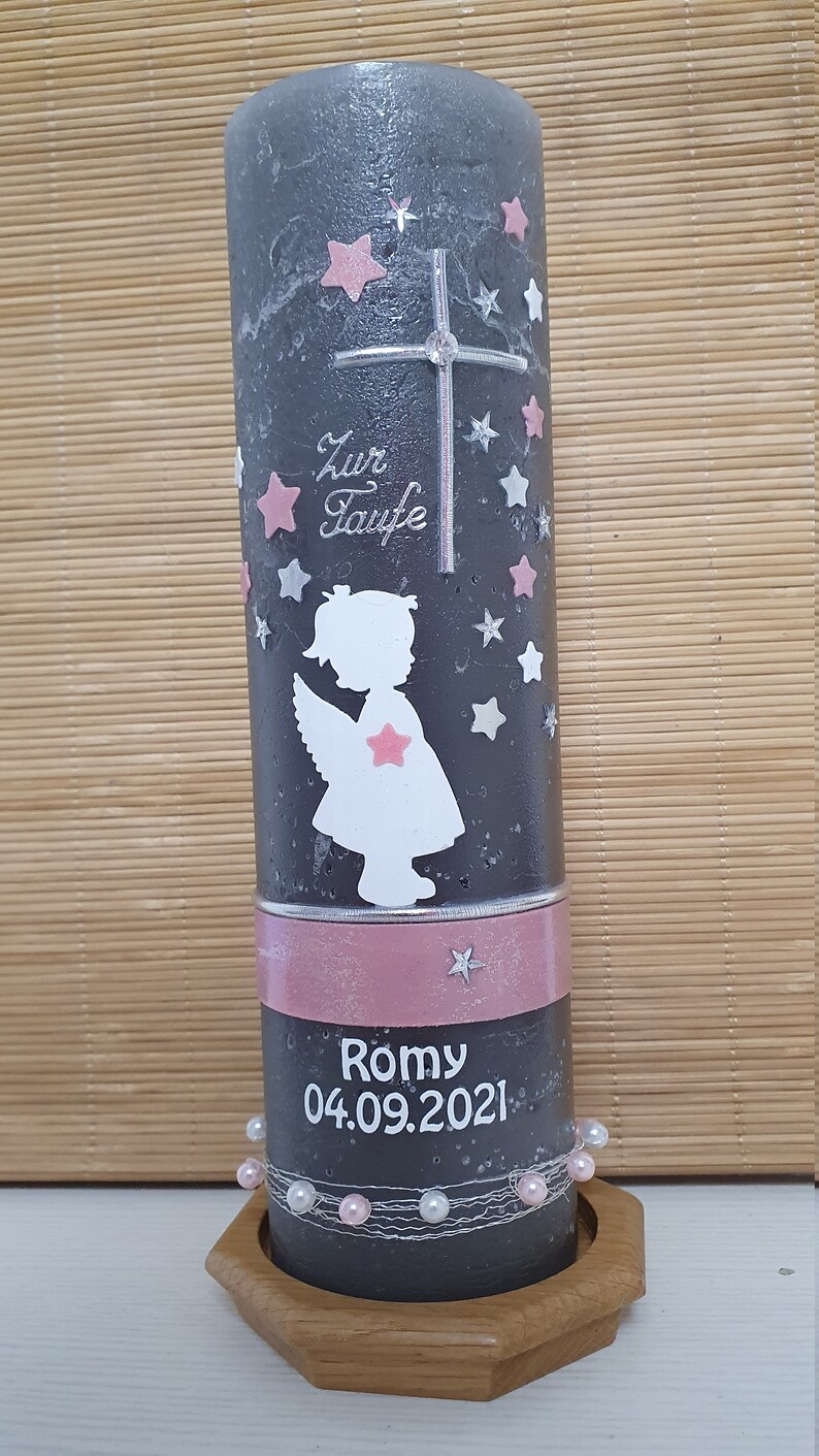 Pu&ograve; includere: Una candela battesimale grigia con un nastro rosa, una silhouette di angelo bianca e stelle rosa. La candela ha il testo "Zur Taufe" e "Romy 04.09.2021" su di essa.