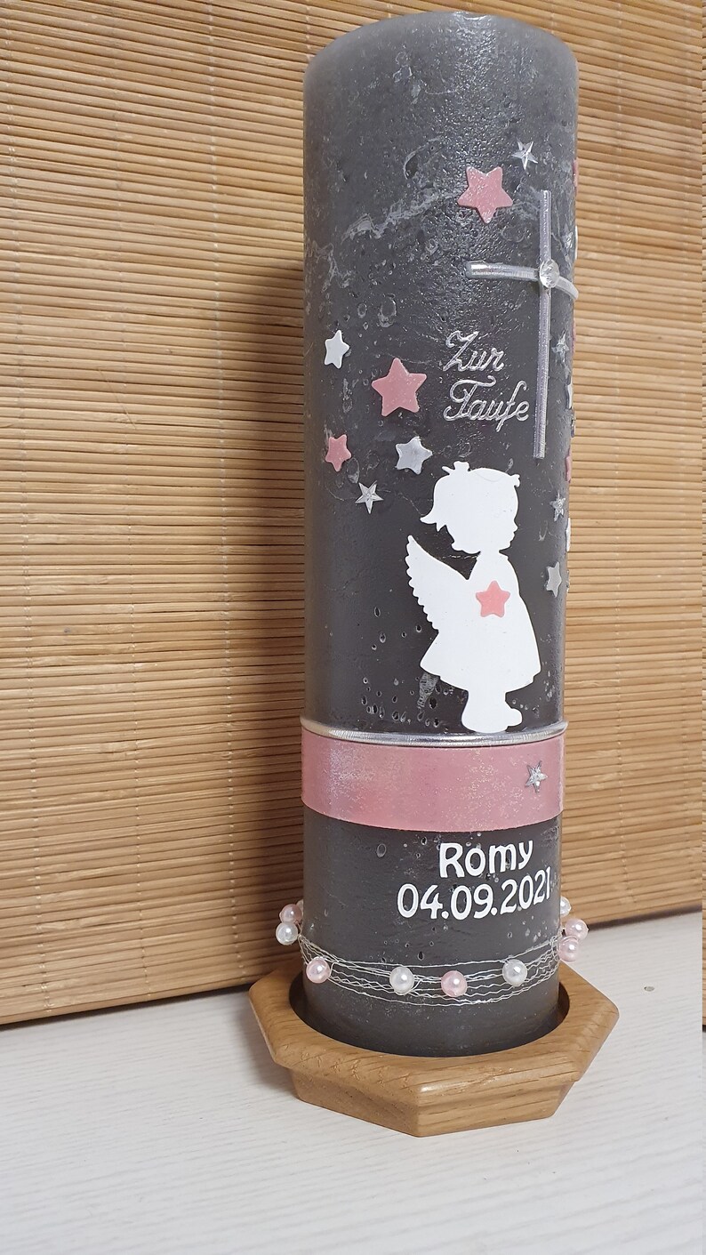 Pu&ograve; includere: Una candela battesimale grigia con un nastro rosa e perline bianche. La candela presenta una silhouette bianca di un angelo con stelle rosa e il testo "Zur Taufe" e "Romy 04.09.2021".