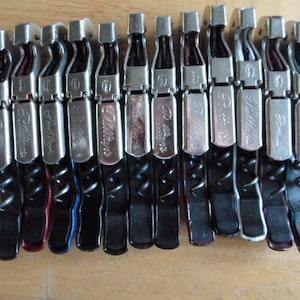 May include: A row of 12 silver and black corkscrews with the word "Pulltaps" printed on each. The corkscrews have black, red, blue, and green handles.