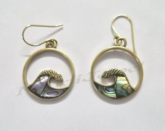 May include: A pair of gold-toned circular drop earrings featuring a stylized wave design. The lower portion of each wave is inlaid with iridescent abalone shell, displaying shades of purple, green, and blue. Each earring hangs from a simple hook.