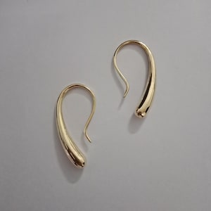 Puede incluir: Un par de pendientes de gota de oro con forma de lágrima curvada.
