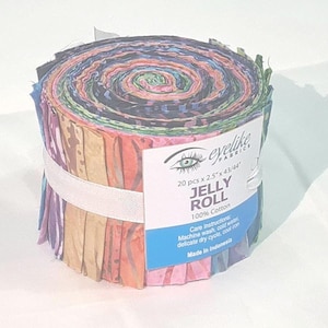 Könnte beinhalten: Ein gerolltes Bündel bunter Stoffstreifen, als "Jelly Roll" mit dem Logo "eyelike fabrics" gekennzeichnet. Die Rolle enthält 20 Teile, jeweils 6,35 cm breit und 109,22/111,76 cm lang, aus 100% Baumwolle. Pflegehinweise sind enthalten.