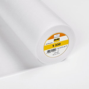 Könnte beinhalten: Eine weiße Rolle Vlieseline S 320 Einlage. Das Etikett ist gelb mit schwarzem Text und zeigt die Produktnummer, das Material und die Größe: 90 cm x 25 m.