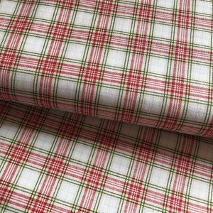 Könnte beinhalten: Roter und grüner karierter Stoff mit weißem Hintergrund. Der Stoff ist in der Mitte gefaltet.