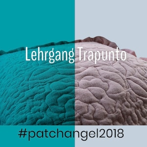 Pode incluir: Uma almofada acolchoada turquesa e bege com uma borda franjada. A almofada tem um padrão floral e o texto "Lehrgang Trapunto #patchangel2018" está impresso na almofada.