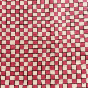 Könnte beinhalten: Nahaufnahme eines Stoffes mit einem rot-weiß-karierten Muster. Die Quadrate sind schwarz umrandet und erzeugen ein kühnes, grafisches Design. Der Stoff hat ein leicht strukturiertes Aussehen.