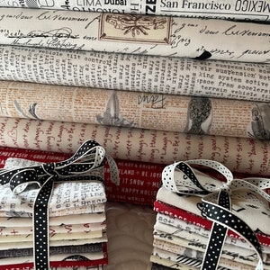 Könnte beinhalten: Ein Stapel Stoffquadrate, die mit einem schwarz-weißen gepunkteten Band zusammengebunden sind. Der Stoff ist weiß mit schwarzem und rotem Text und Designs. Der Text enthält Sätze wie "Merry & Bright", "Happy Holidays" und "Good Tidings".