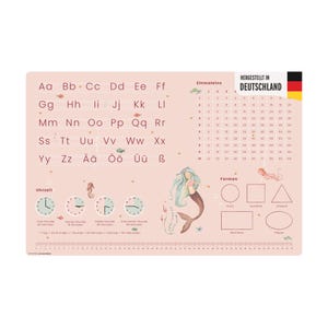 Puede incluir: Un mantel individual educativo rosa con el alfabeto, números, formas y una ilustración de sirena. El mantel individual incluye el texto "HERGESTELLT IN DEUTSCHLAND" y relojes. Adecuado para el aprendizaje de los niños.