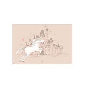 Könnte beinhalten: Ein rechteckiger Tischset mit einem weißen Einhorn, das vor einem Schloss galoppiert. Der Hintergrund ist hellbraun mit ein paar Sternen und einem kleinen rosa Herz. Das Einhorn hat eine fließende Mähne und einen Schweif.