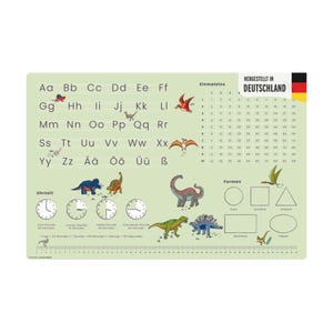 Puede incluir: Un mantel individual educativo verde claro con el alfabeto, los números, las formas y los relojes. El mantel individual incluye ilustraciones de dinosaurios y el texto "HERGESTELLT IN DEUTSCHLAND".