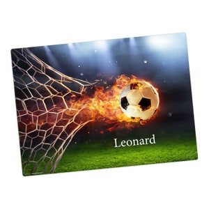 Peut inclure: Un ballon de football en feu traverse le filet d'un but. Le ballon est englouti par les flammes et le filet est déchiré. Le nom "Leonard" est écrit sous le ballon.