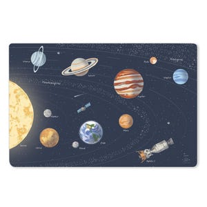 Könnte beinhalten: Ein rechteckiger Tischset mit einer farbenfrohen Illustration des Sonnensystems. Planeten wie Jupiter, Saturn und Erde sind abgebildet, zusammen mit der Sonne und dem Raumschiff Apollo 11. Der Hintergrund ist dunkelblau.