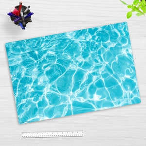 Può includere: Primo piano di un motivo astratto blu e bianco, che ricorda la superficie di una piscina. Il motivo è composto da vortici e increspature blu chiaro e bianche.