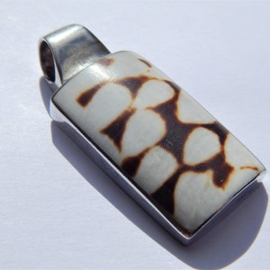 May include: A silver pendant with a rectangular white shell inlay featuring a brown and white pattern.