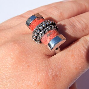 Puede incluir: Un anillo de plata con una piedra de coral rojo engastada en una banda de plata. La banda est&aacute; decorada con una fila de cuentas de plata.