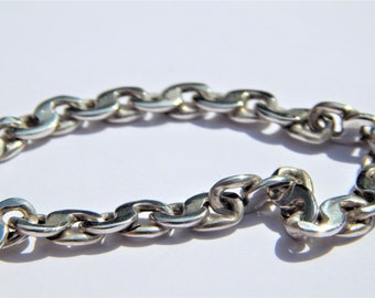 May include: A silver chain bracelet with a curb link design. The bracelet is made of polished metal and has a shiny finish.