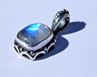 May include: A silver pendant with a square moonstone set in a detailed silver frame. The pendant has a beaded bail.