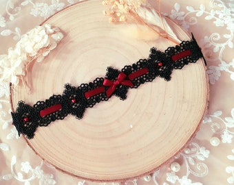 May include: Black lace choker with a red satin ribbon bow and black beads.