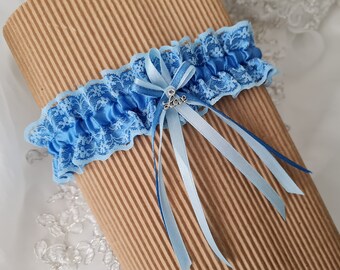 Könnte beinhalten: Ein hellblaues Hochzeitsstrumpfband mit zarter Spitzenborte und Satinband. Das Strumpfband hat eine kleine Schleife mit einem silbernen Anhänger mit der Aufschrift "love". Das Strumpfband ist etwa 3,8 cm breit.