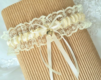May include: A delicate ivory lace garter with a satin bow and a gold heart charm.